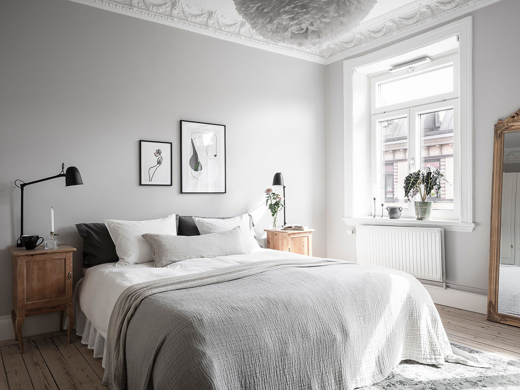 A light grey bedroom with grey textiles and vintage bedside tables