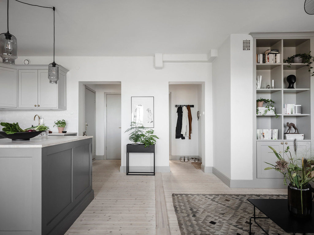 A grey living kitchen with a built-in bookshelf in the same style as the kitchen