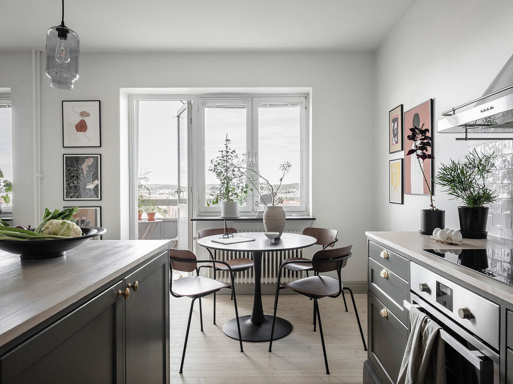 A black round kitchen dining table combined with walnut dining chairs with steel legs in a grey kitchen