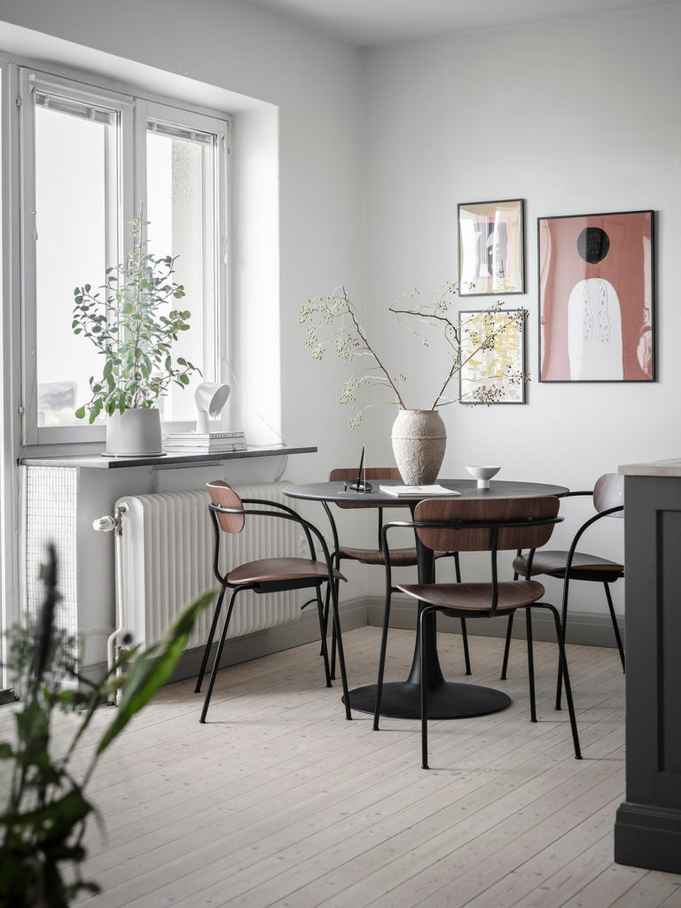 A black round kitchen dining table combined with walnut dining chairs with steel legs in a grey kitchen