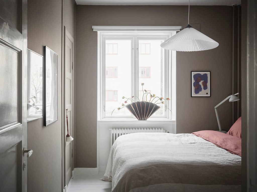 A bedroom with warm grey walls and a white floor
