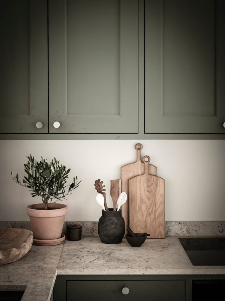 An olive green kitchen with a biege limestone countertop in a small studio home