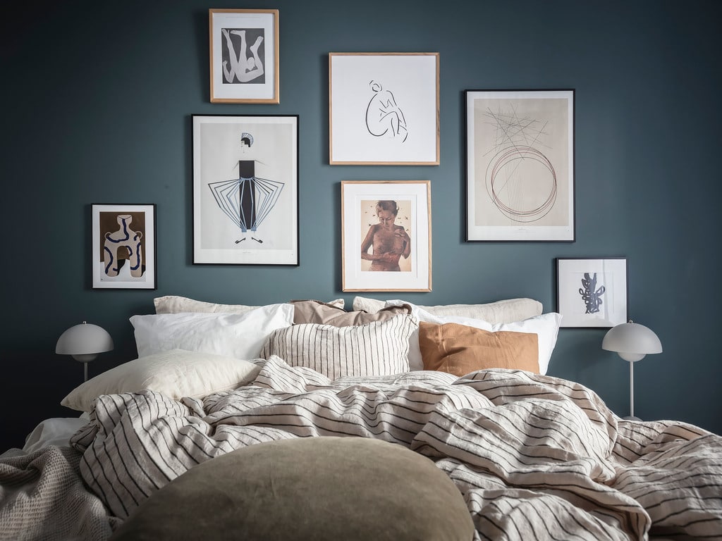 A bedroom with dark blue walls and a gallery wall