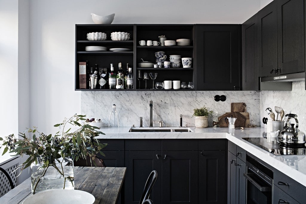 A kitchen with black cabinets, black hardware, white marble countertops