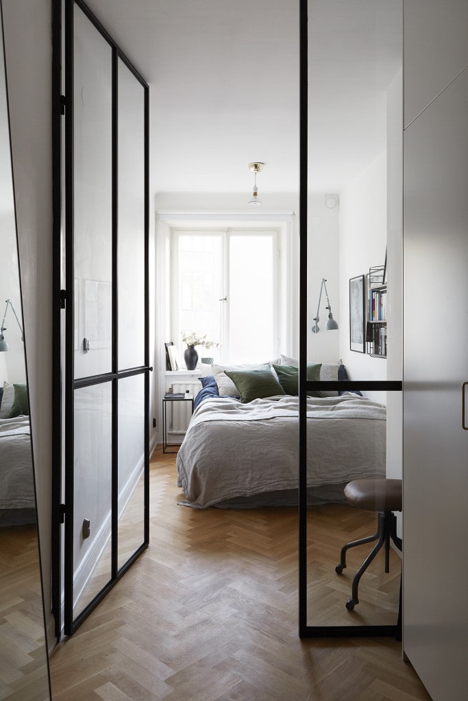 A big black metal glass door to enter a small bedroom