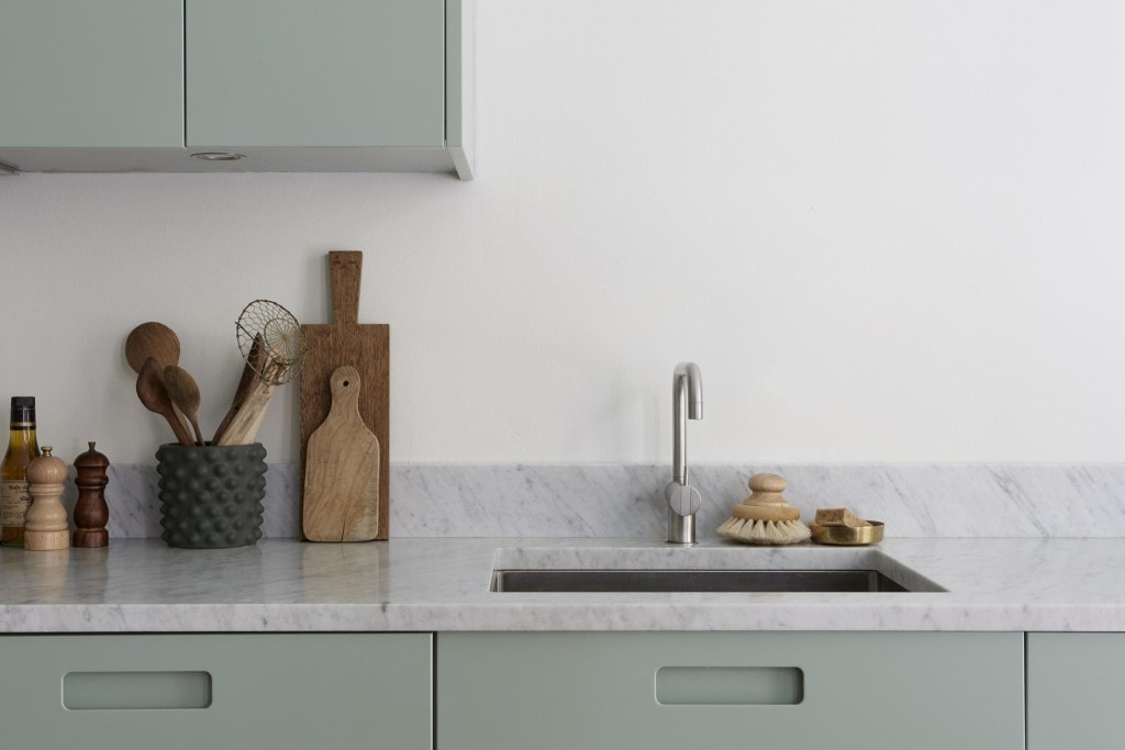 A minimal mint green kitchen with white marble countertops