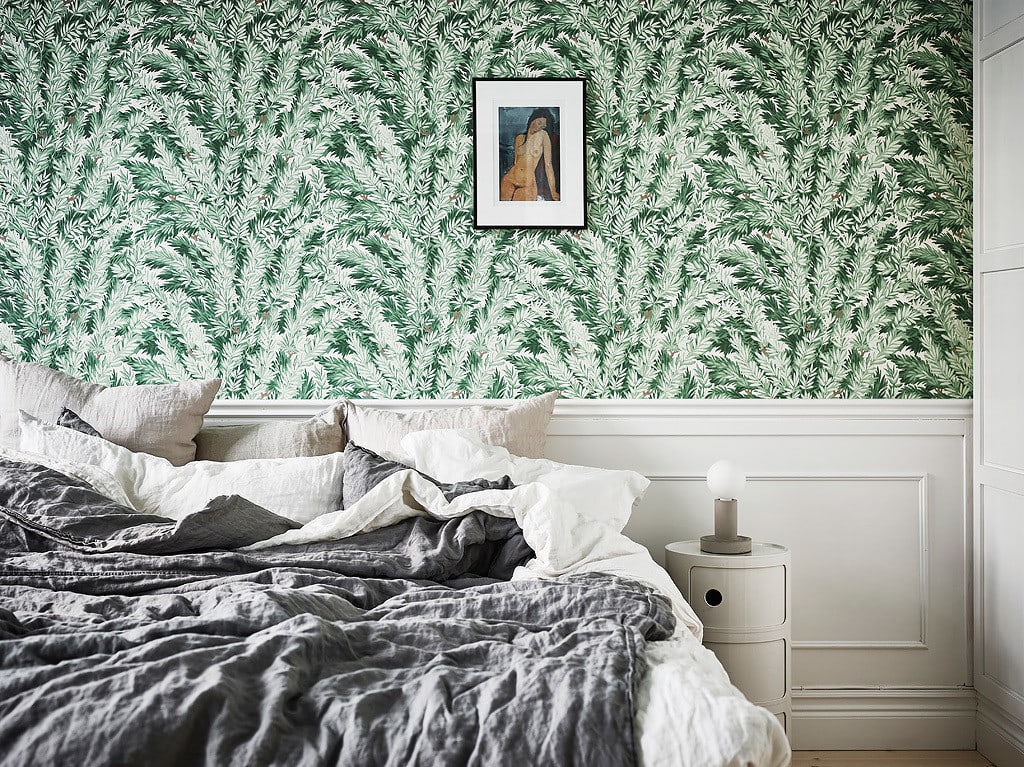 A tropical green wallpaper above white wainscoting in a white and grey bedroom