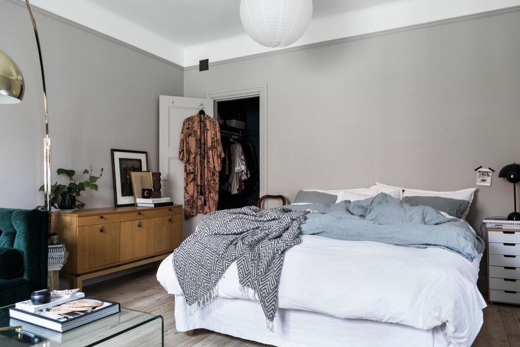 A bedroom with grey walls and white bedding