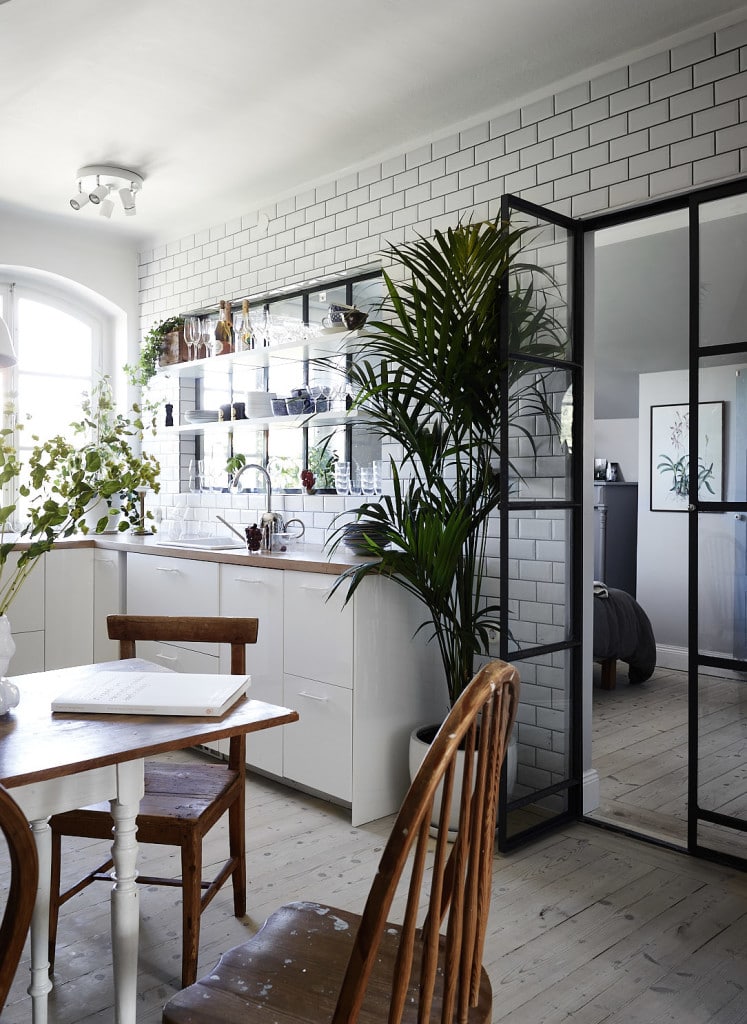 A black metal interior window and a swing door separating the kitchen and the bedroom in a small apartment