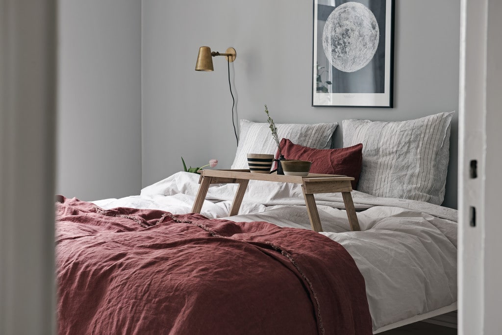 A light grey bedroom with burgundy textiles on the bed