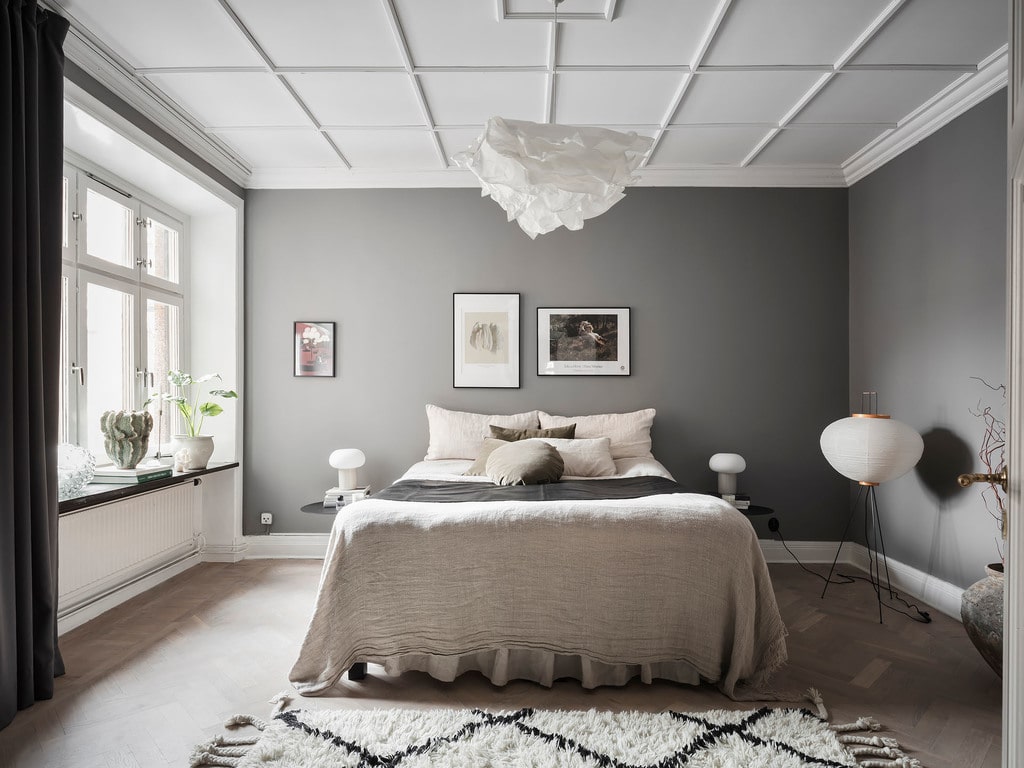 Grey bedroom walls accentuate an impressive ceiling pattern abd a nice selection of art prints