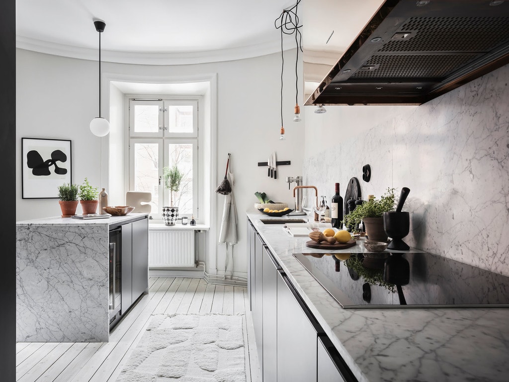 A white marble kitchen island with dark grey kitchen cabinets