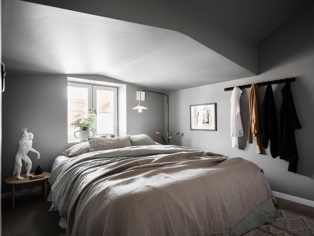 An attic bedroom with a low ceiling and grey wall color