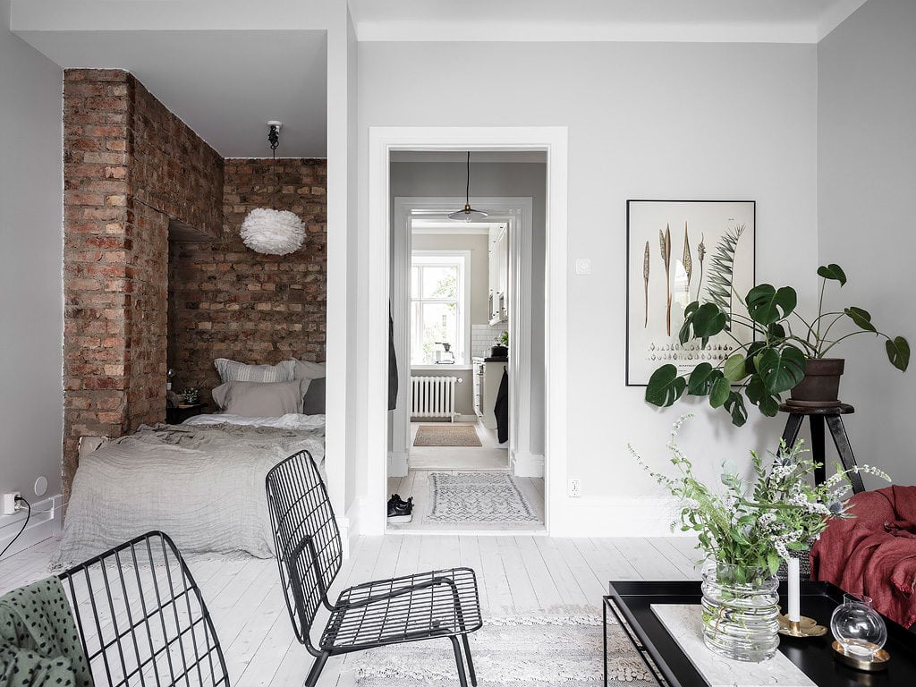 A studio apartment bedroom with a stripped brick wall
