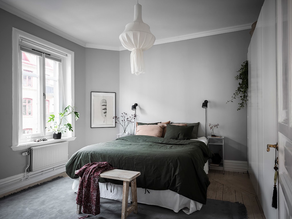 A light grey bedroom with dark green linen bedding