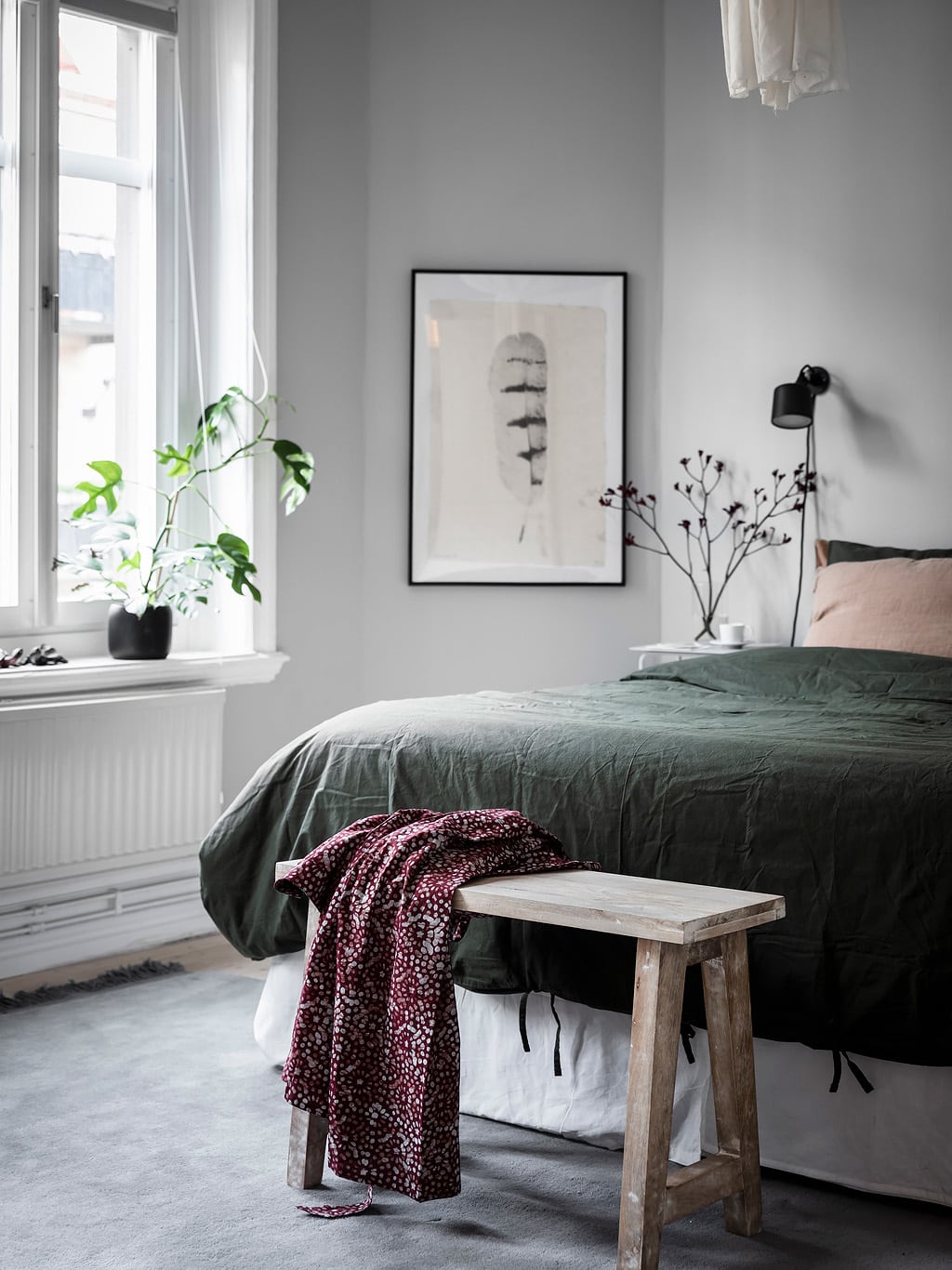 A light grey bedroom with dark green linen bedding