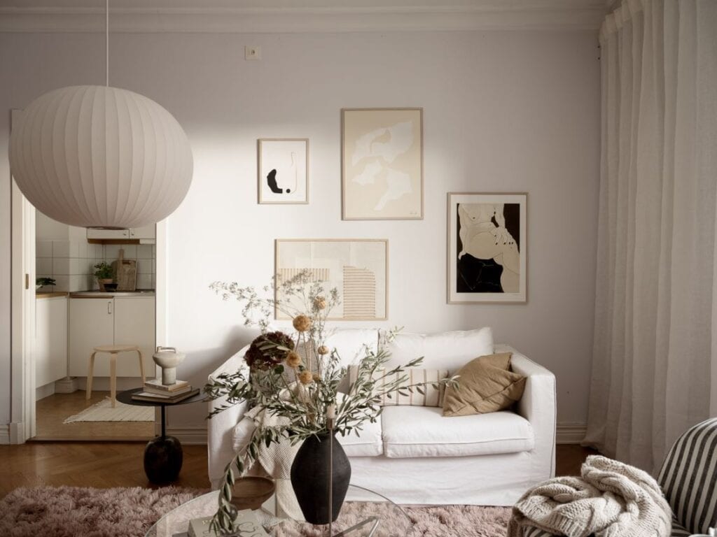 A living room with a white sofa and a gallery wall in beige and black tones, paired with a pink area rug