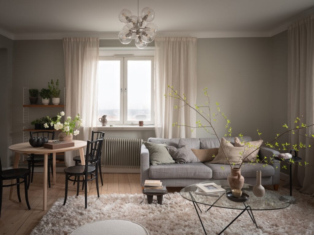A green-grey living room with a white rug and a grey fabric sofa