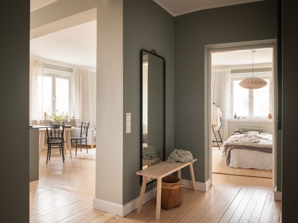 A hallway with a green-grey wall color  and a custom storage solution