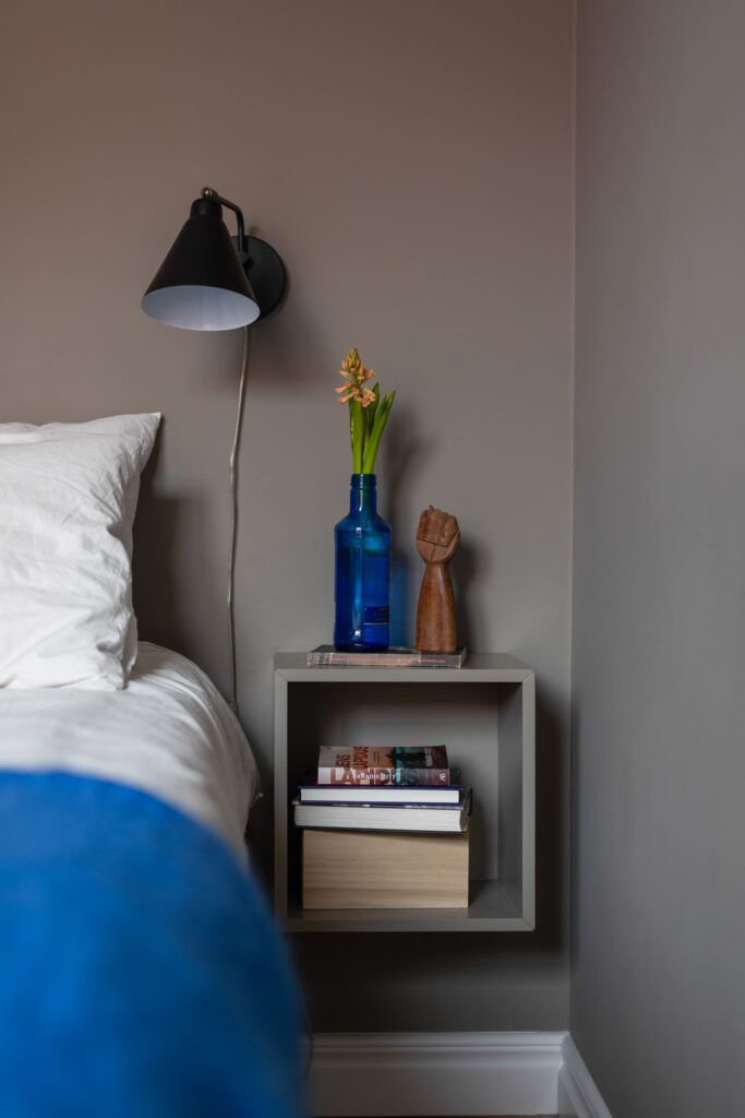 A bedroom with a dark grey wall color and blue textiles and accessories