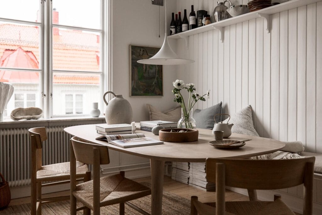 A breakfast nook with shiplap walls, oak dining table and chairs, bench against the wall