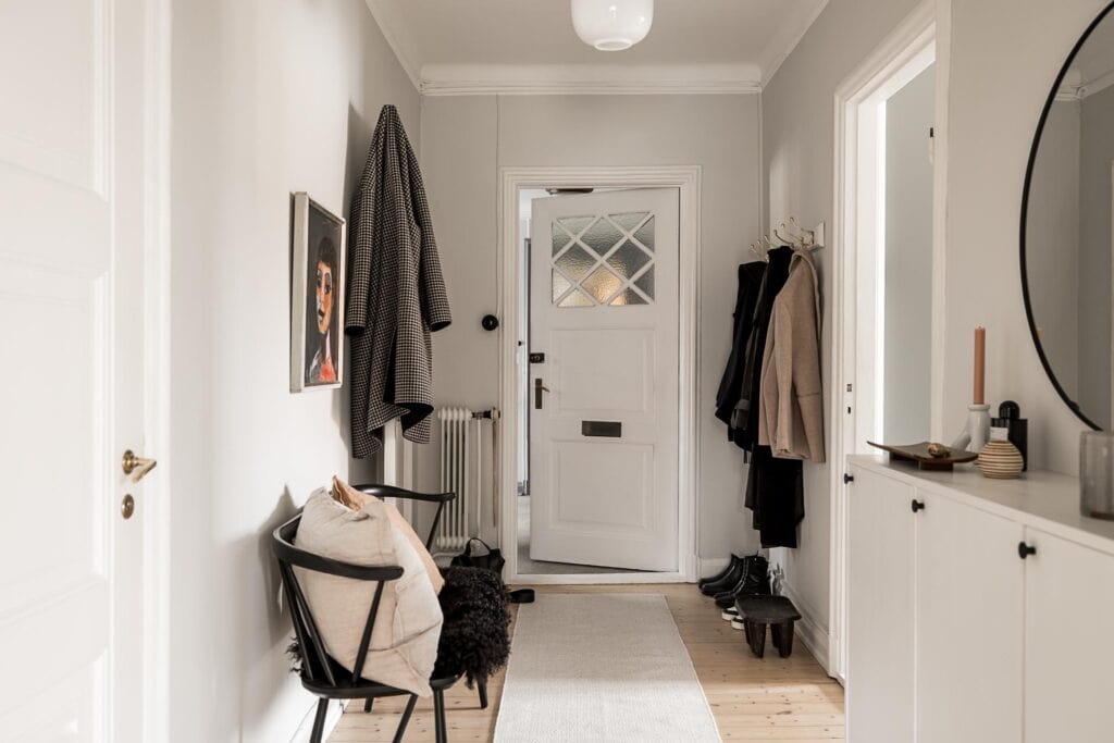 An entryway with light grey walls and a black and white decor palette