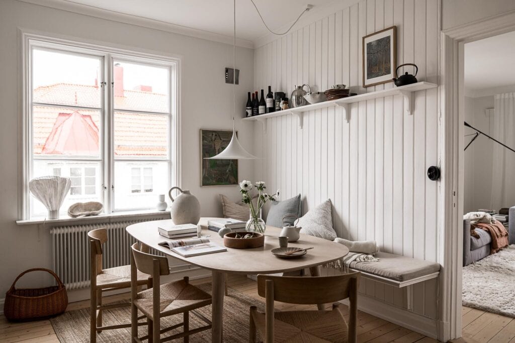 A breakfast nook with shiplap walls, oak dining table and chairs, bench against the wall