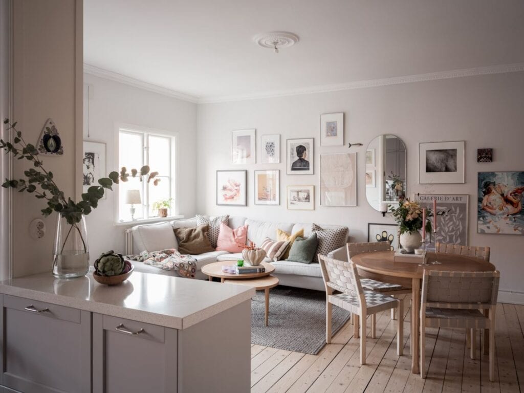 A living room with a light grey sofa, vintage dining table and pastel colors in the decor