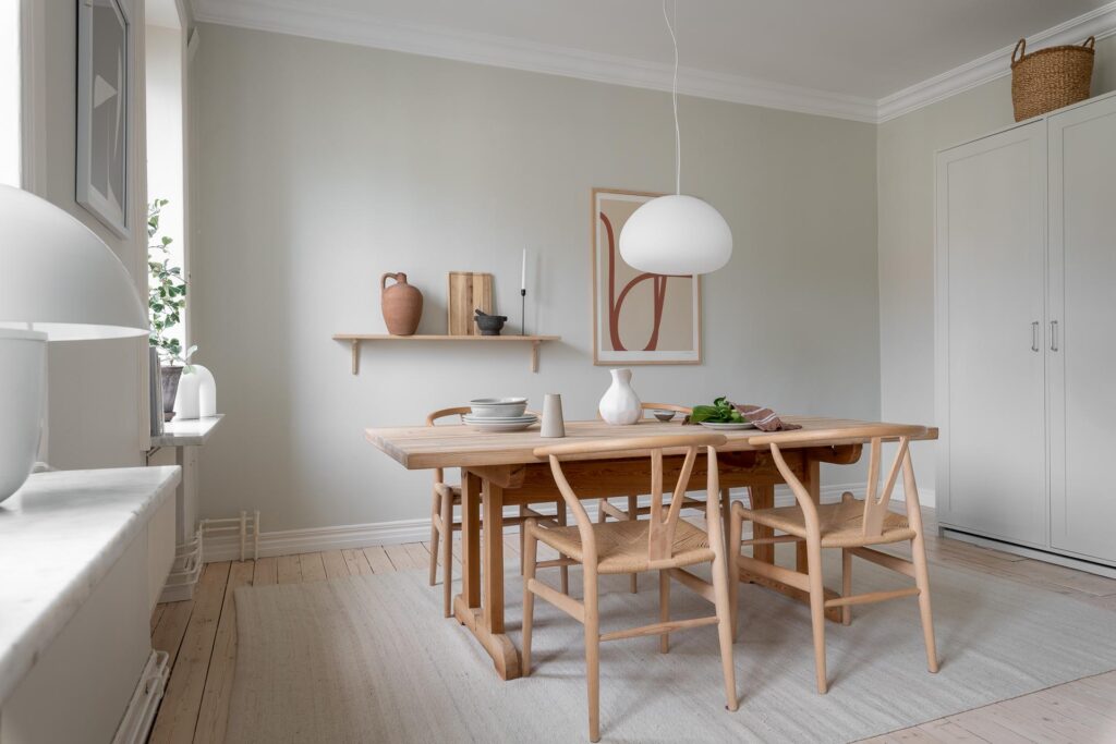 A light grey shaker kitchen with a large dining table and Wishbone Dining chairs