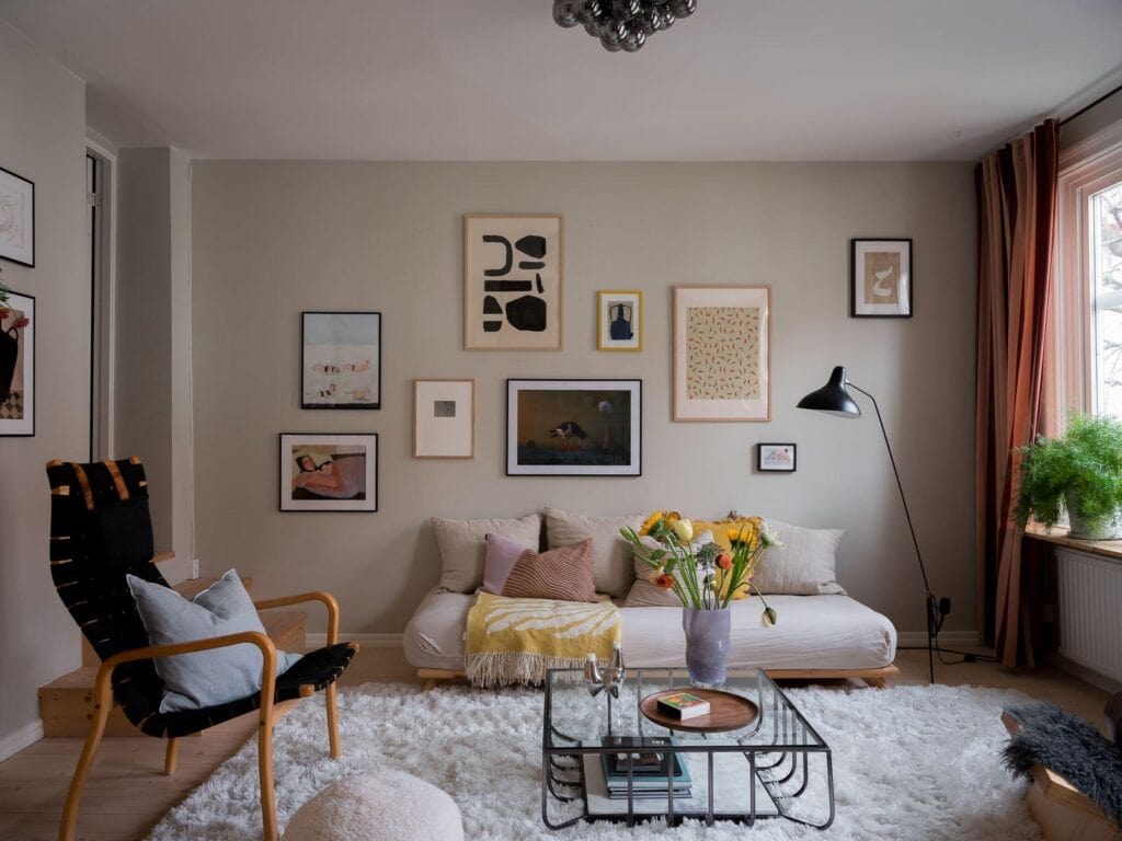 A living room with muted beige walls and a pastel color palette in the accessories and textiles