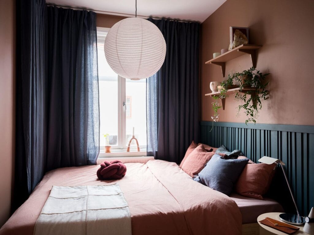 A bedroom with pink walls and blue wainscoting
