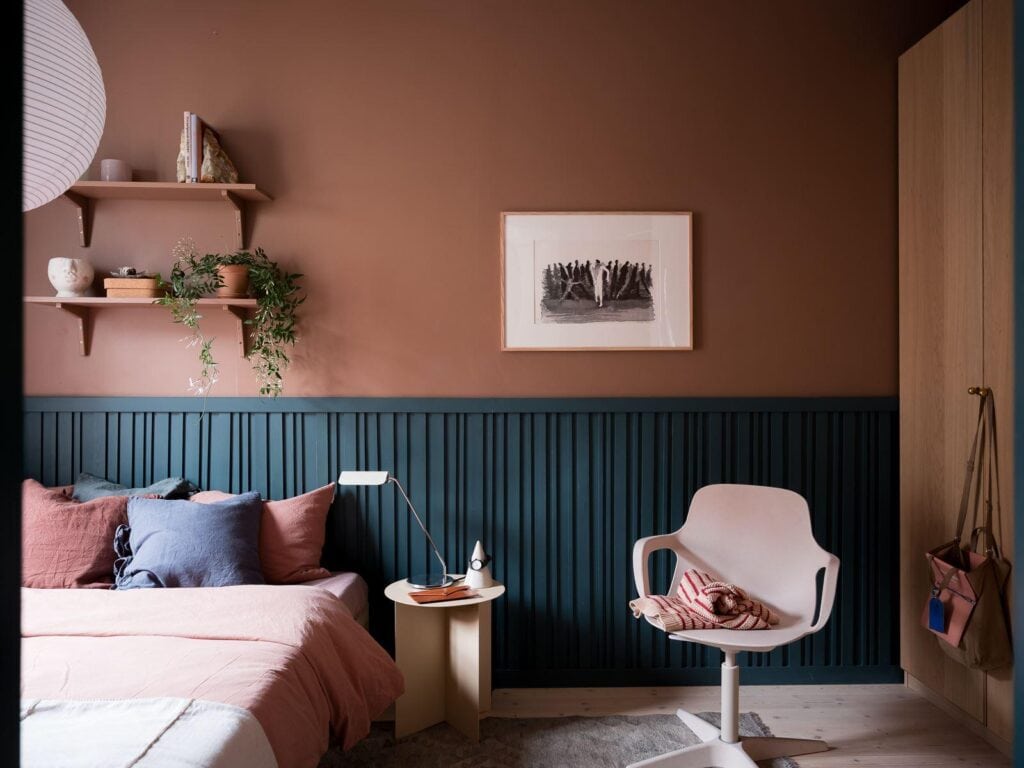 A bedroom with pink walls and blue wainscoting