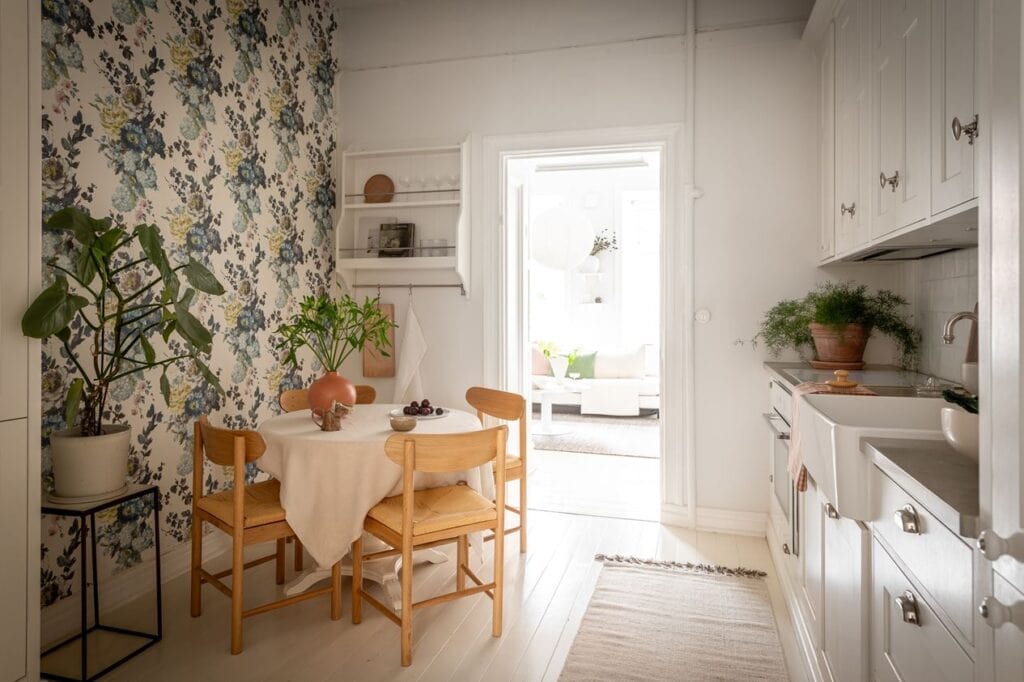 A kitchen dining area with oak dining chairs and floral wallpaper