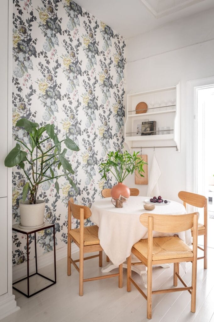 A kitchen dining area with oak dining chairs and floral wallpaper