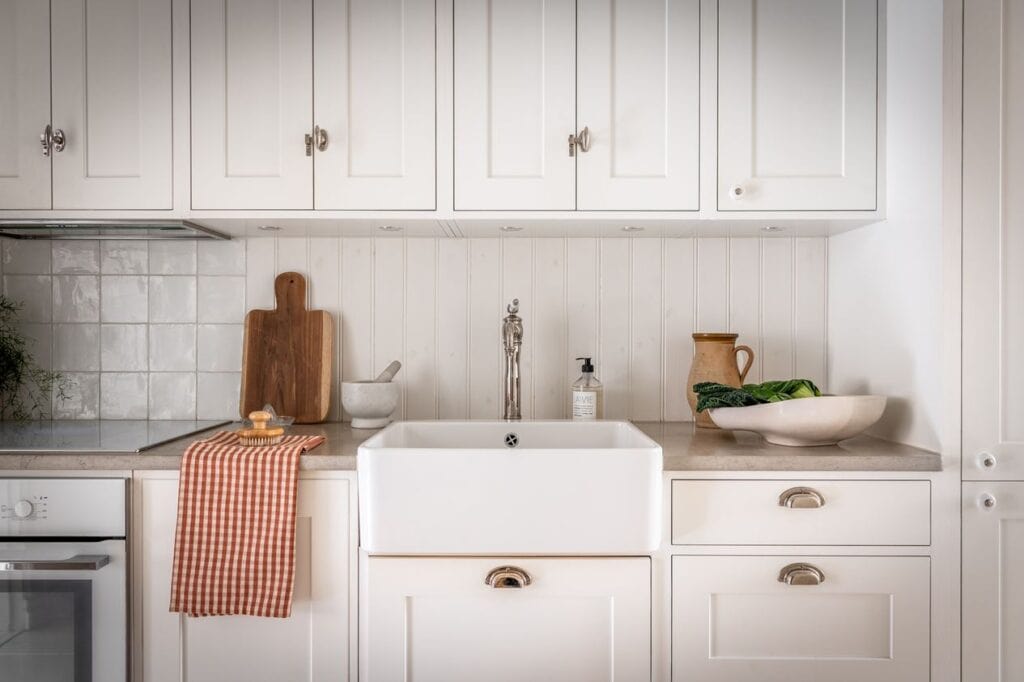 A white shaker kitchen with stainless steel hardware a tile and shiplap backsplash