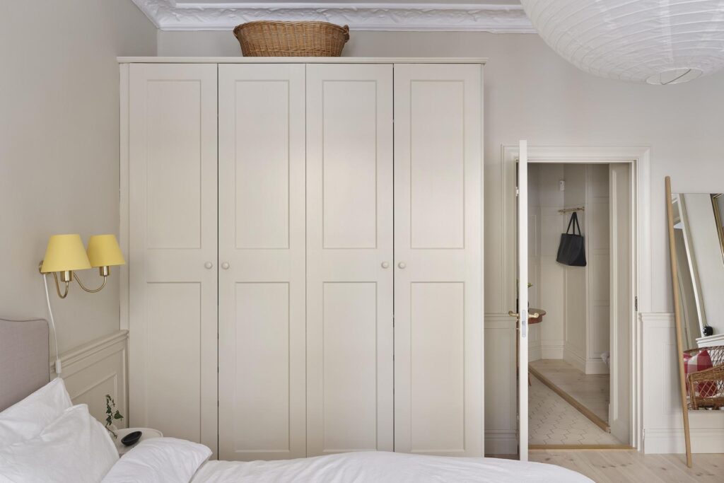 A classic bedroom with custom wardrobe painted in the same color as the walls