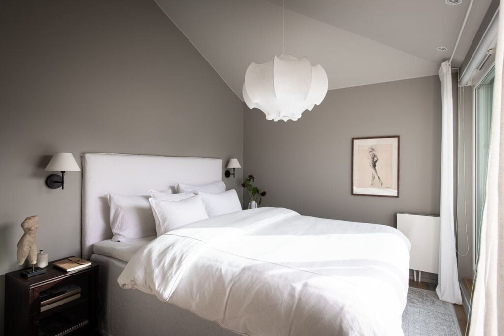 A simple attic bedroom with sand walls and crisp white bedding
