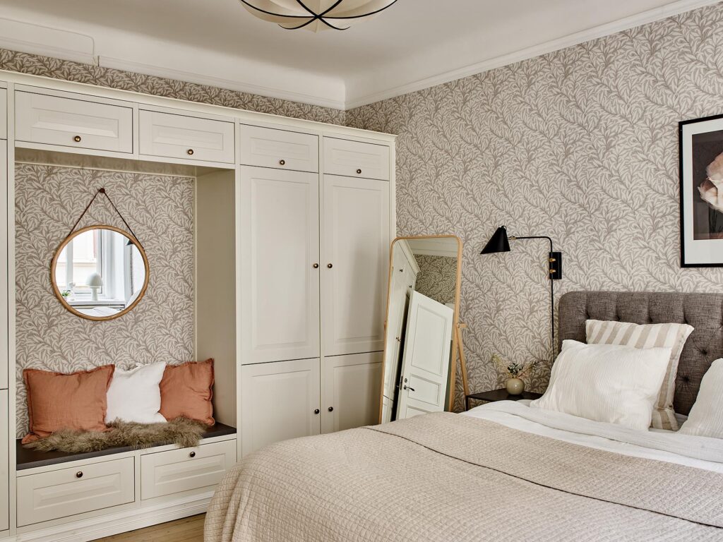 A beige pattern bedroom wallpaper paired up with a white wardrobe with a seating nook