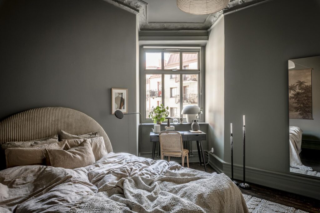 A green-grey wall color in a bedroom with a n asymetric floor plan