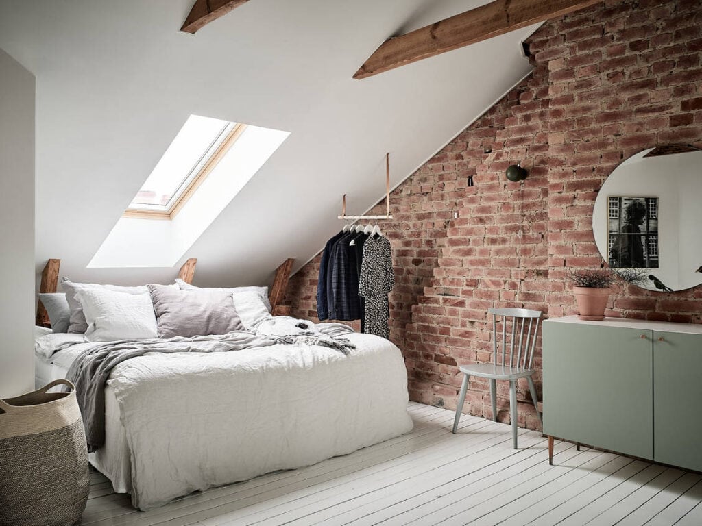An attic bedroom with a skylight and an exposed brick wall