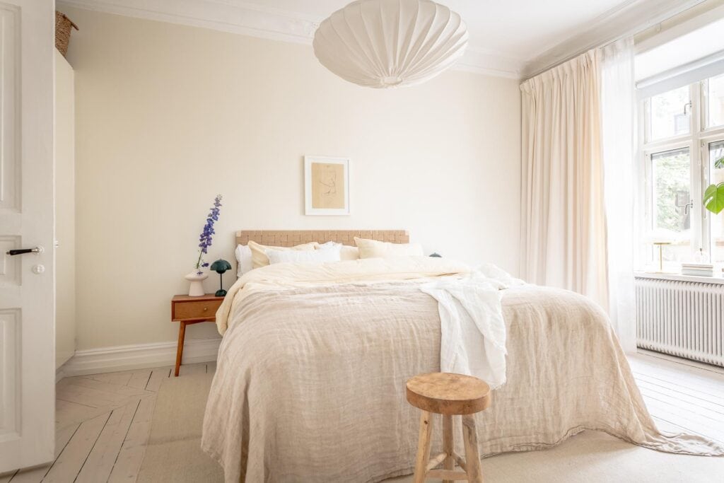 A light beige bedroom with a statement headboard and blue tones in the bedside lamps