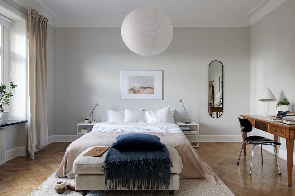 A light grey bedroom with navy blue and beige accent tones