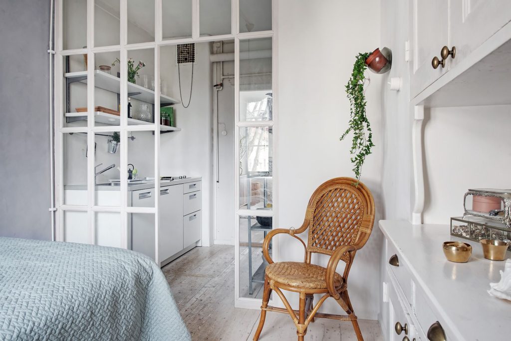 A white glass partition wall in between the kitchen and bedroom of a small apartment