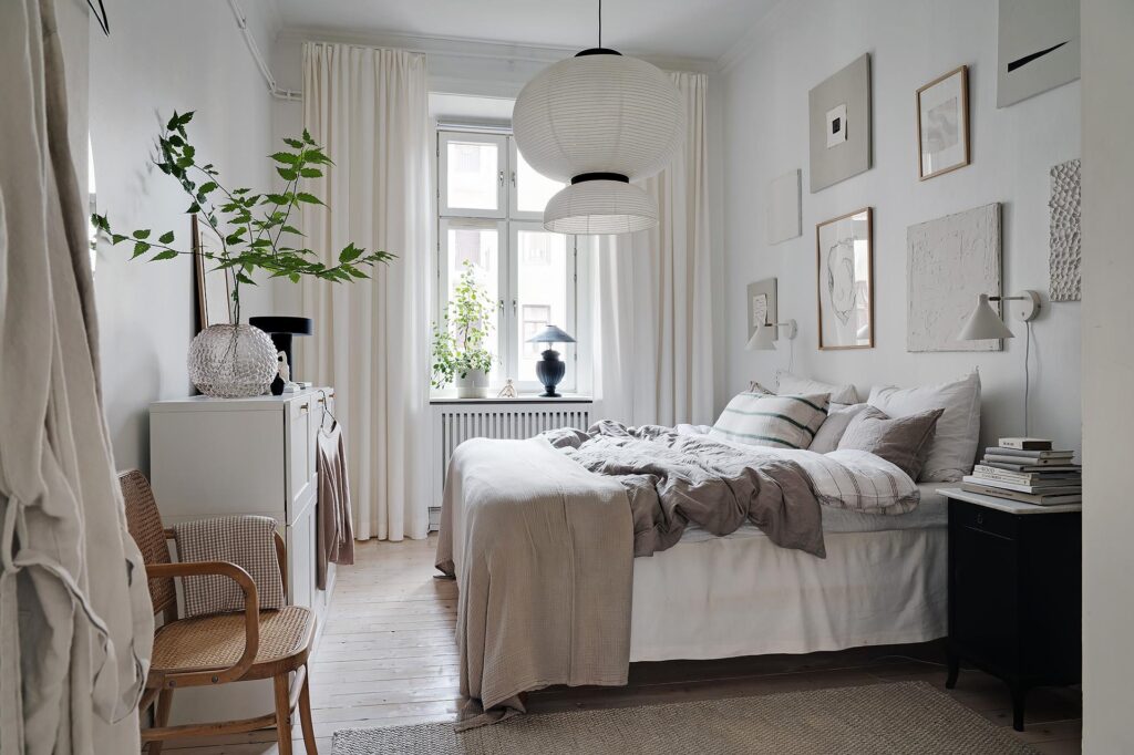 A bedroom with a light and neutral color palette that comes back in the gallery wall above the bed