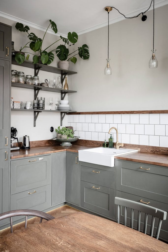 An olive green kitchen with wood countertops and a subway tile backsplash