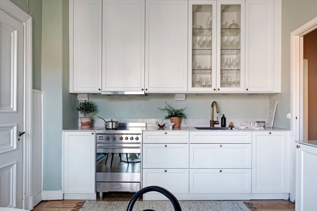 A white shaker kitchen with brass hardware and stainless steel appliances
