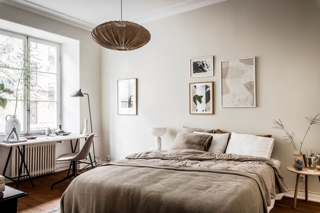 A bedroom with beige tones and off-white walls finished off with a simple gallery wall