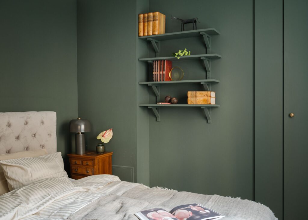 A dark green wall color on the bedroom walls, closet doors and wall shelving