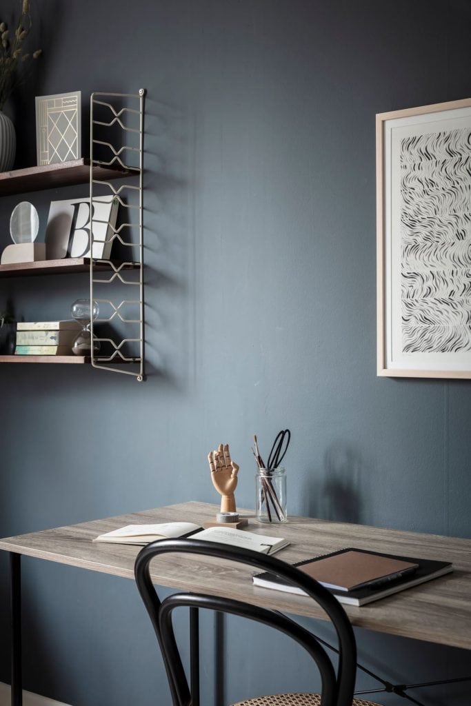 A bedroom with a deep blue wall color, home office spot