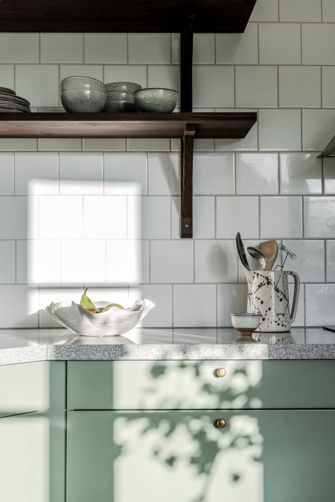 An apple green kitchen with a subway tile backsplash and black accents